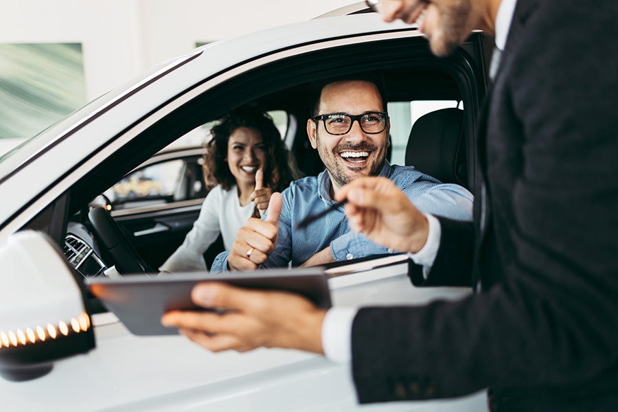 Dealer Explaining Car Features To Happy Customers